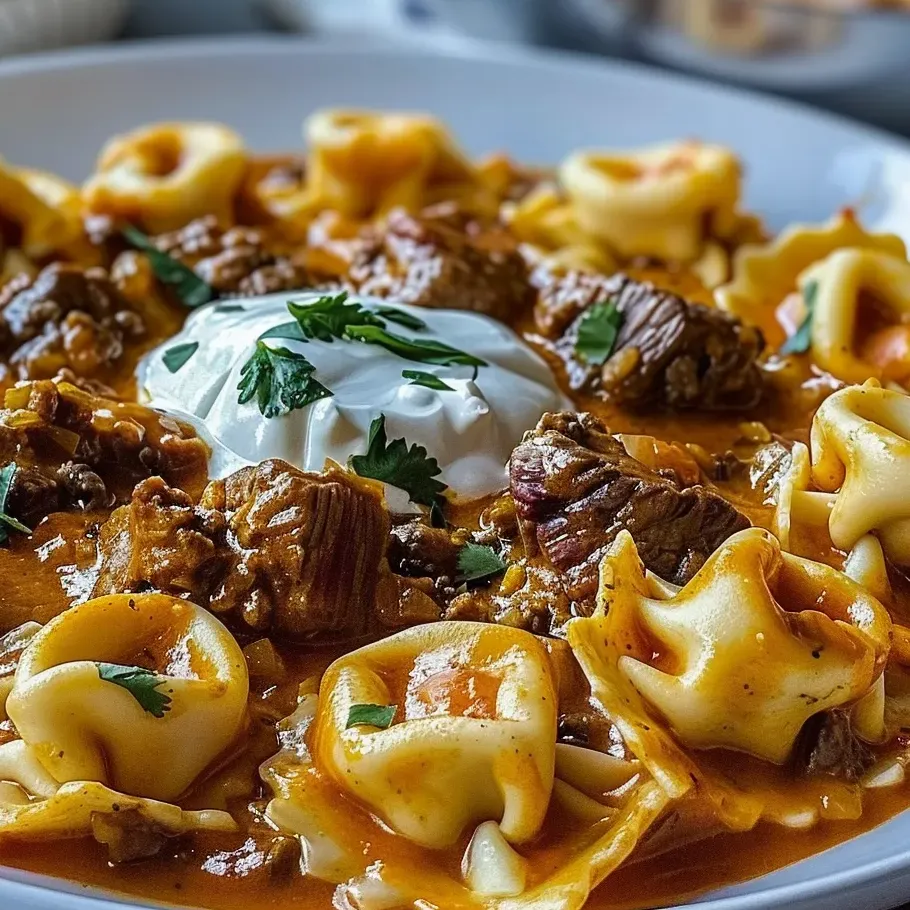 A steaming plate of cheesy pasta mixed with beef in enchilada sauce.