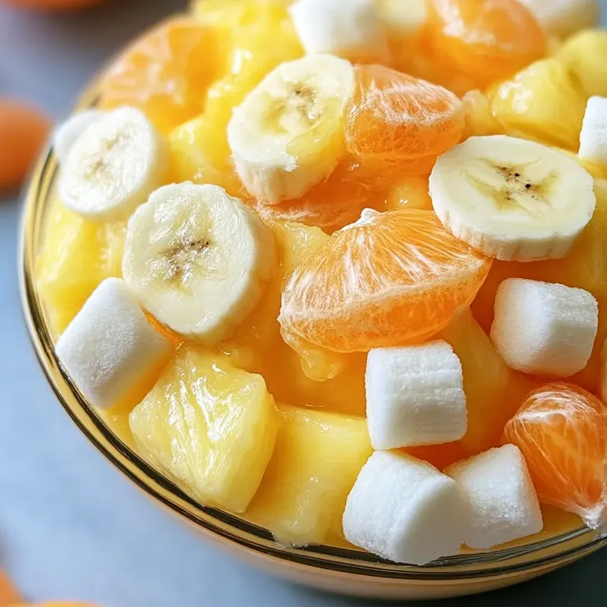 A bowl of fruit salad with bananas, oranges, and marshmallows.