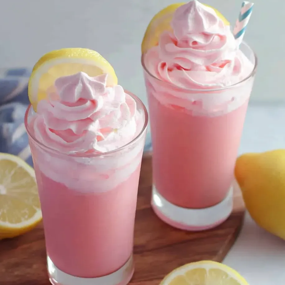 Two glasses of pink lemonade with lemon slices on a table.