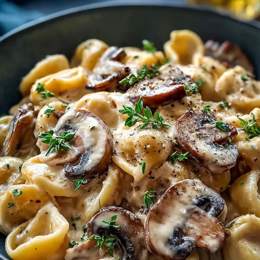A bowl of pasta with mushrooms and herbs.