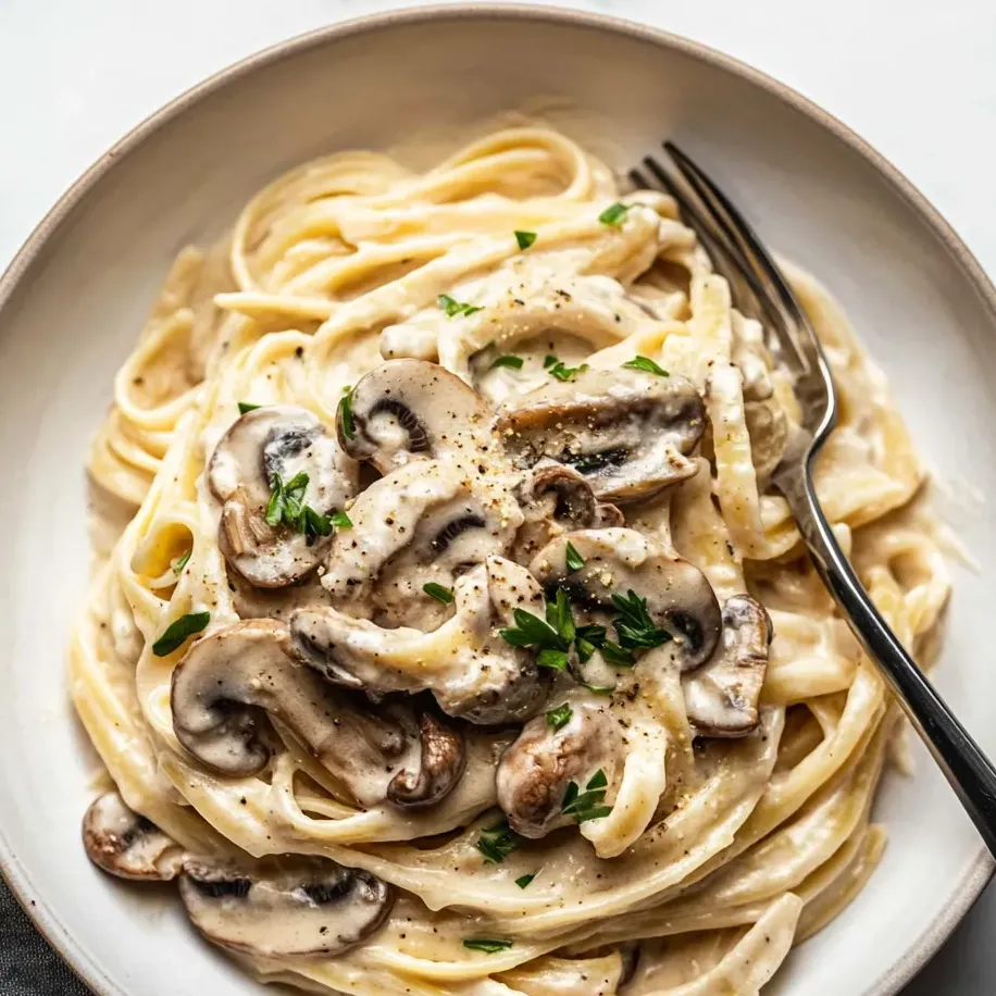 A bowl of pasta with mushrooms and herbs.