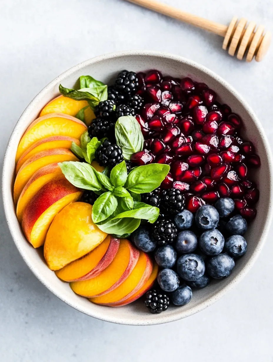 A bowl of fruit with blueberries, raspberries, peaches, and blackberries.