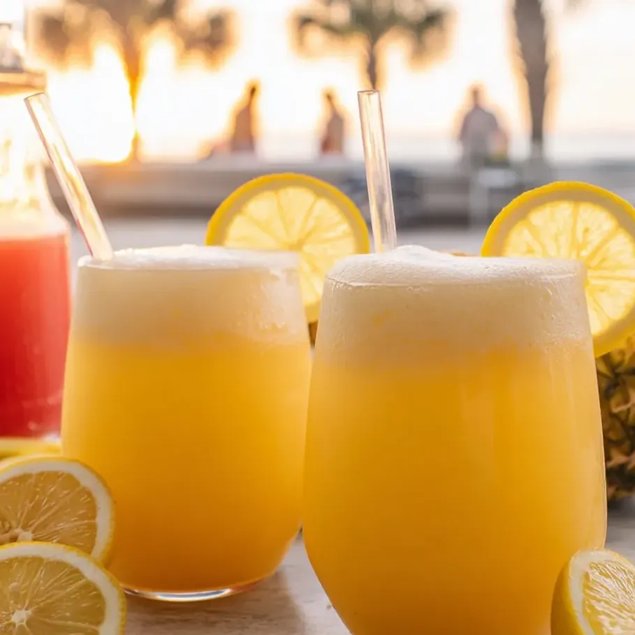 Two glasses of lemonade with lemon slices in them.