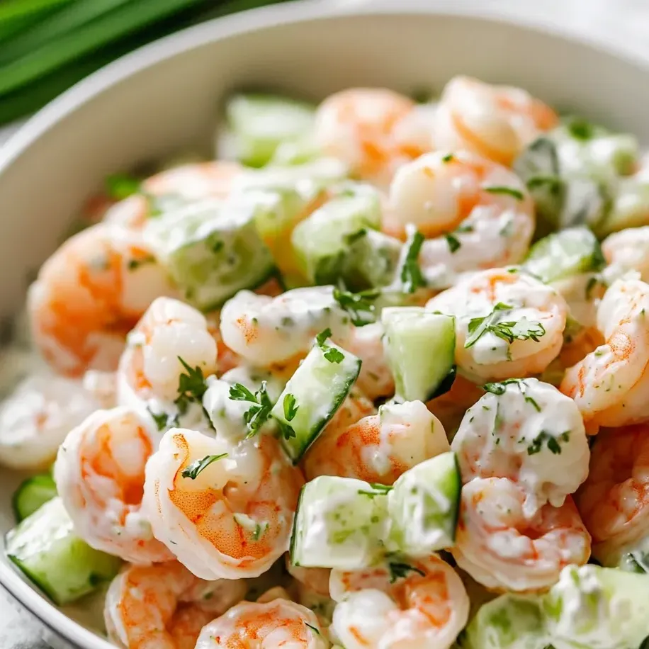 A bowl of shrimp salad with cucumbers and other vegetables.