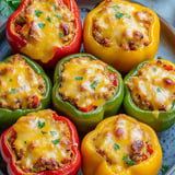 Four stuffed bell peppers with cheese and herbs.