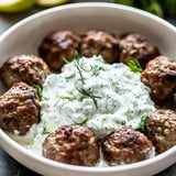 A bowl of meatballs with a white sauce on top.