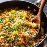 A pan of rice with peas and carrots.