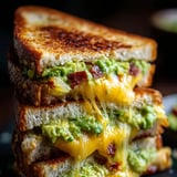 A stack of sandwiches with avocado and cheese.