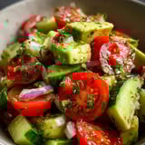 A bowl of sliced tomatoes, cucumbers, onions, and peppers.