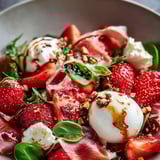 A plate of food with strawberries, ham, and cheese.