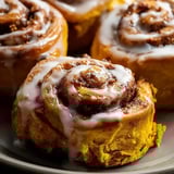 Two rolls of cinnamon rolls on a plate.