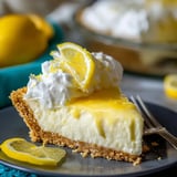 A slice of lemon cheesecake with a lemon wedge on the side.