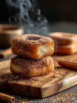 A stack of cinnamon donuts on a wooden cutting board.