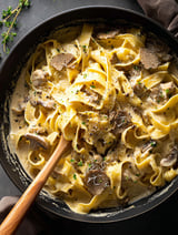 A bowl of pasta with mushrooms and truffle oil.