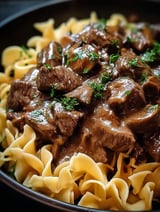 A bowl of beef tips and noodles.