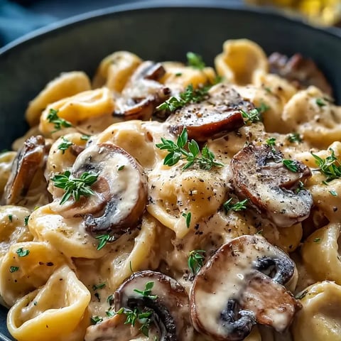 A bowl of pasta with mushrooms and herbs.