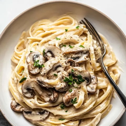 A bowl of pasta with mushrooms and herbs.