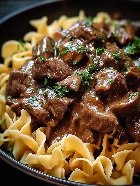 A bowl of beef tips and noodles.